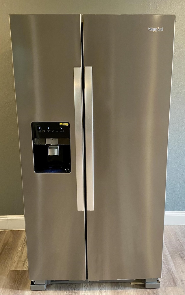 room details with stainless steel fridge and light wood-type flooring