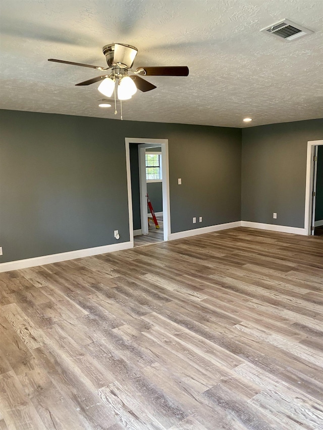 unfurnished room with ceiling fan, light hardwood / wood-style floors, and a textured ceiling