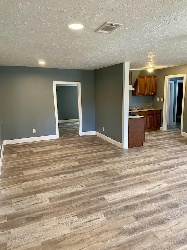 unfurnished living room with a textured ceiling and light wood-type flooring