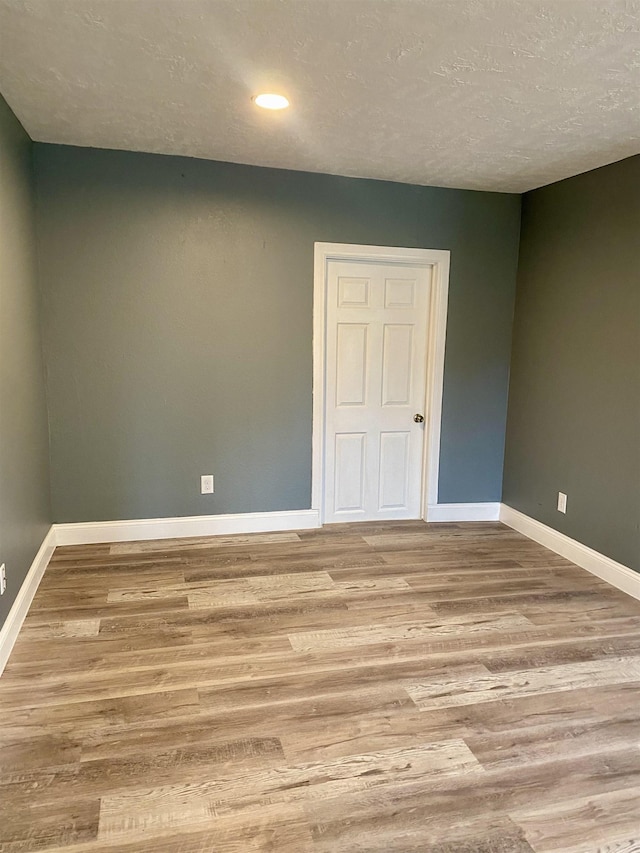 spare room featuring light hardwood / wood-style flooring and a textured ceiling