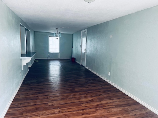 spare room featuring a textured ceiling and dark hardwood / wood-style flooring