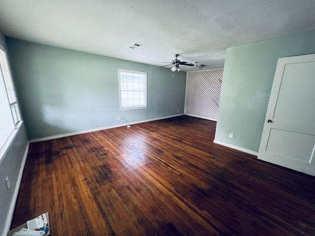 spare room featuring dark hardwood / wood-style floors, ceiling fan, and a textured ceiling