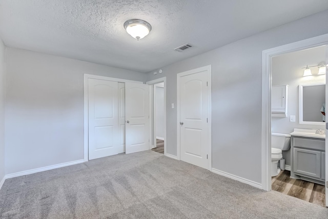 175 Triangle Dr, Vidor, TX 77662 - unfurnished bedroom featuring baseboards, carpet flooring, a textured ceiling, a closet, and ensuite bath