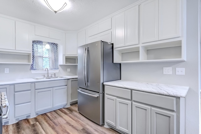175 Triangle Dr, Vidor, TX 77662 - kitchen with open shelves, a sink, appliances with stainless steel finishes, light wood finished floors, and white cabinetry