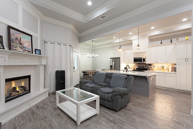 7495 Broussard Rd, Beaumont, TX 77713 - living room with a raised ceiling, crown molding, wood finished floors, a chandelier, and a lit fireplace