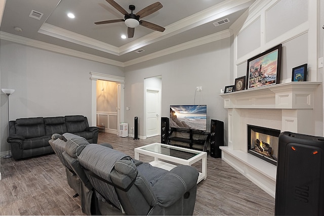 7495 Broussard Rd, Beaumont, TX 77713 - living room featuring ceiling fan, wood finished floors, a warm lit fireplace, crown molding, and a tray ceiling