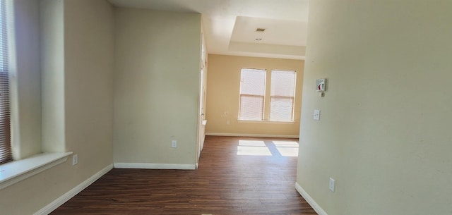 hall with a tray ceiling and dark wood-type flooring