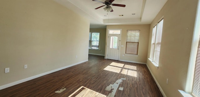 foyer entrance with a raised ceiling, ceiling fan, and dark hardwood / wood-style floors