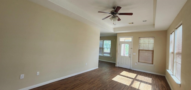 foyer entrance featuring ceiling fan, dark hardwood / wood-style floors, and a tray ceiling