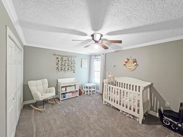 carpeted bedroom featuring crown molding, a closet, baseboards, a nursery area, and a ceiling fan