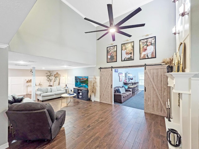 living area with high vaulted ceiling, dark wood-style floors, a barn door, and ceiling fan