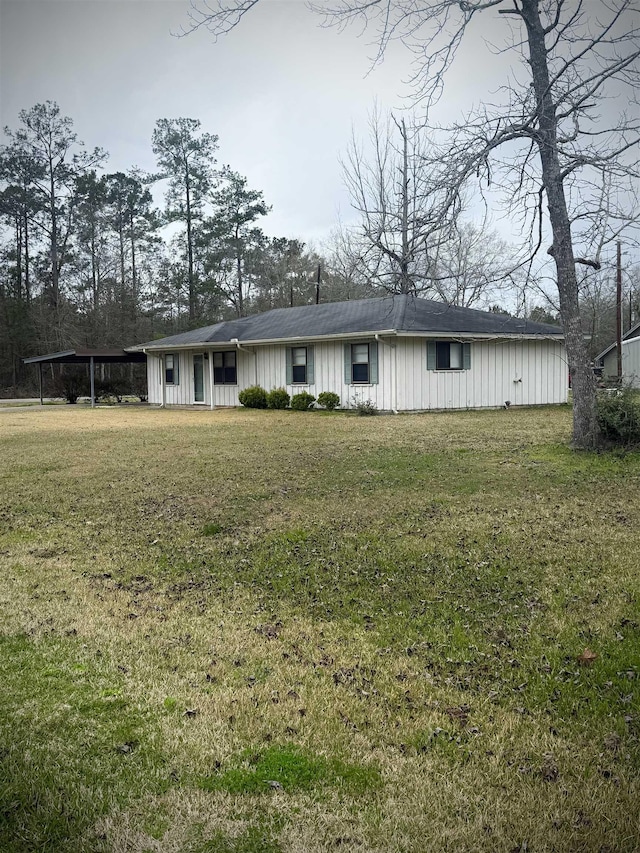 view of front of property with an attached carport, a front lawn, and board and batten siding