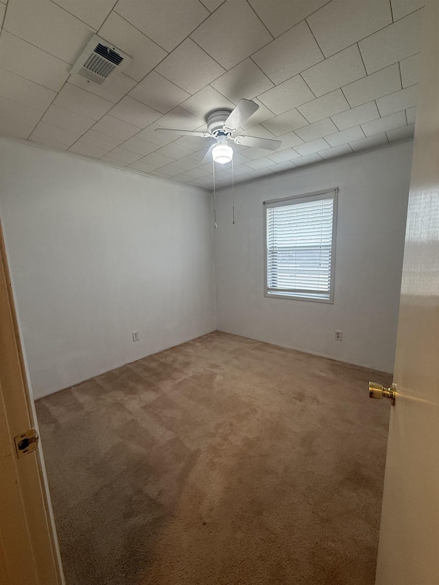 carpeted spare room featuring visible vents and a ceiling fan