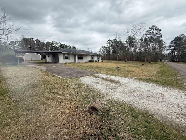 ranch-style home featuring driveway, a carport, board and batten siding, and a front yard