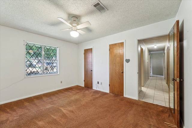 1004 Louise Dr, Nederland, TX 77627 - unfurnished bedroom featuring a textured ceiling, two closets, a ceiling fan, visible vents, and light colored carpet