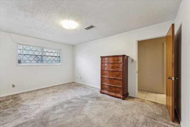 1004 Louise Dr, Nederland, TX 77627 - unfurnished bedroom featuring visible vents, tile patterned flooring, carpet floors, and a textured ceiling