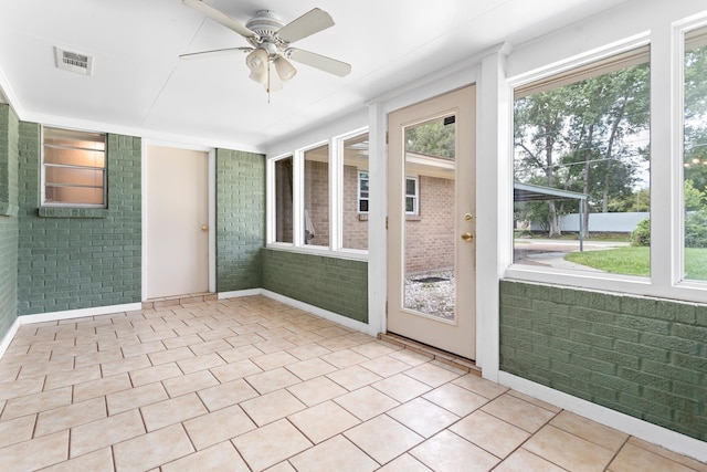 unfurnished sunroom featuring ceiling fan and a wealth of natural light