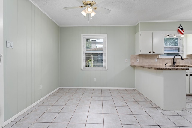 kitchen featuring light tile patterned floors, white cabinetry, crown molding, and dark stone countertops