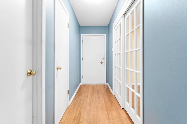 corridor with light hardwood / wood-style floors and a textured ceiling