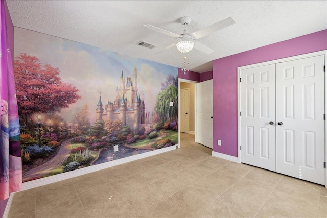 tiled bedroom featuring a closet, visible vents, ceiling fan, a textured ceiling, and baseboards