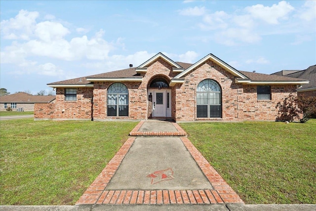 ranch-style home with a front yard, brick siding, and roof with shingles