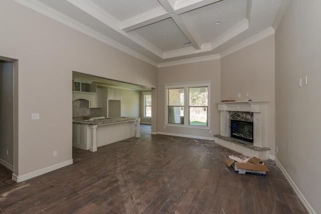 unfurnished living room with coffered ceiling, a high end fireplace, crown molding, dark wood-type flooring, and beam ceiling