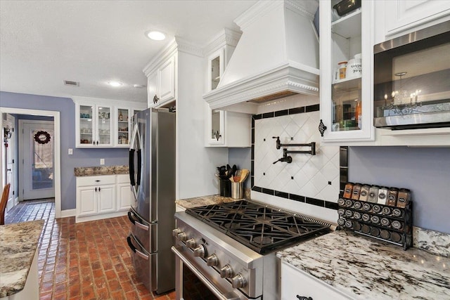 5880 Longwood St, Beaumont, TX 77707 - kitchen featuring premium range hood, appliances with stainless steel finishes, brick flooring, white cabinetry, and light stone counters