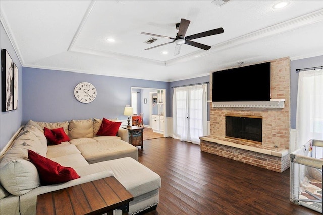 5880 Longwood St, Beaumont, TX 77707 - living room featuring a tray ceiling, wood finished floors, a ceiling fan, crown molding, and a brick fireplace