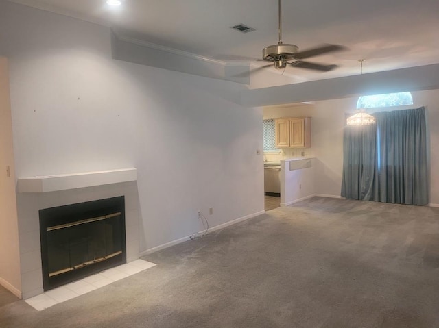 unfurnished living room with a tile fireplace, ceiling fan, light carpet, and ornamental molding