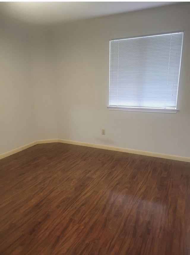 empty room featuring a healthy amount of sunlight and dark wood-type flooring