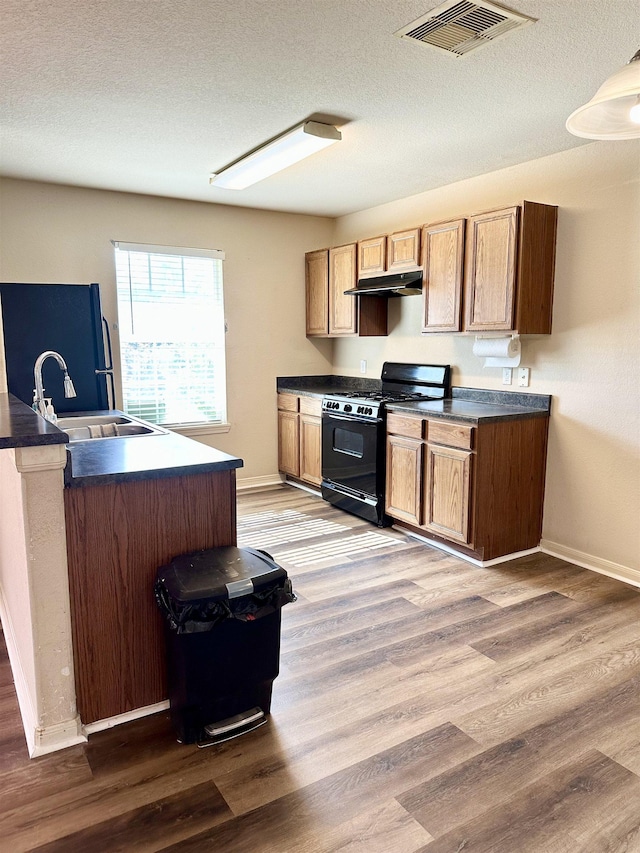 kitchen with refrigerator, wood-type flooring, sink, a textured ceiling, and black gas range