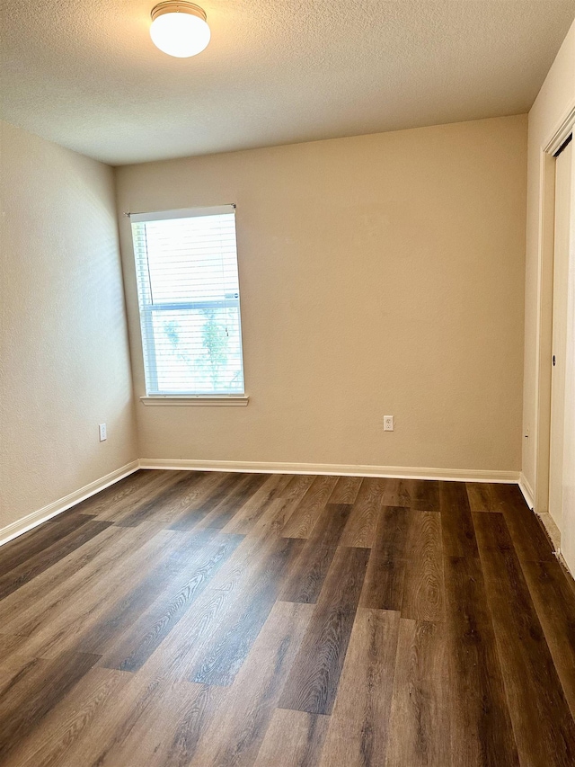 unfurnished room with dark wood-type flooring and a textured ceiling