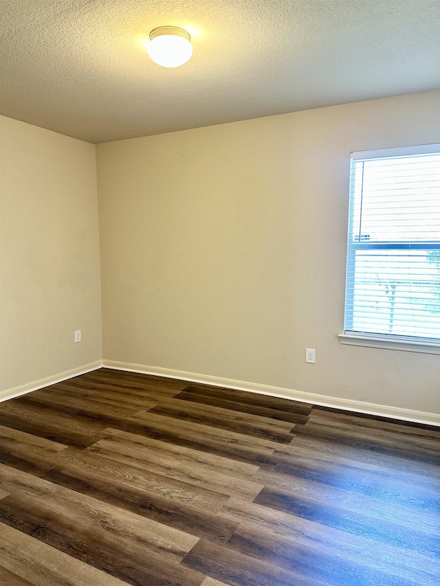 empty room with dark hardwood / wood-style flooring and a textured ceiling