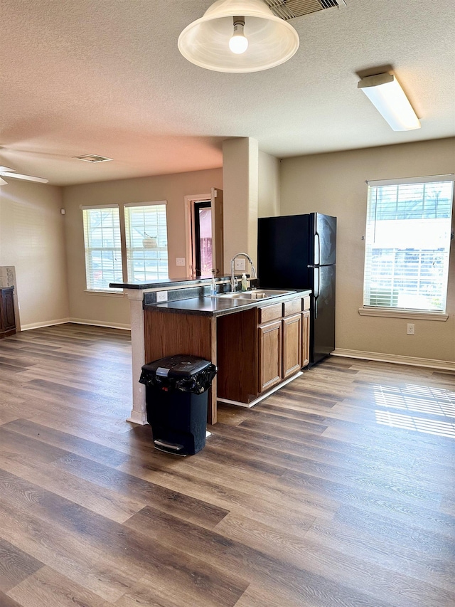 kitchen with dark wood-type flooring, a breakfast bar, kitchen peninsula, and sink