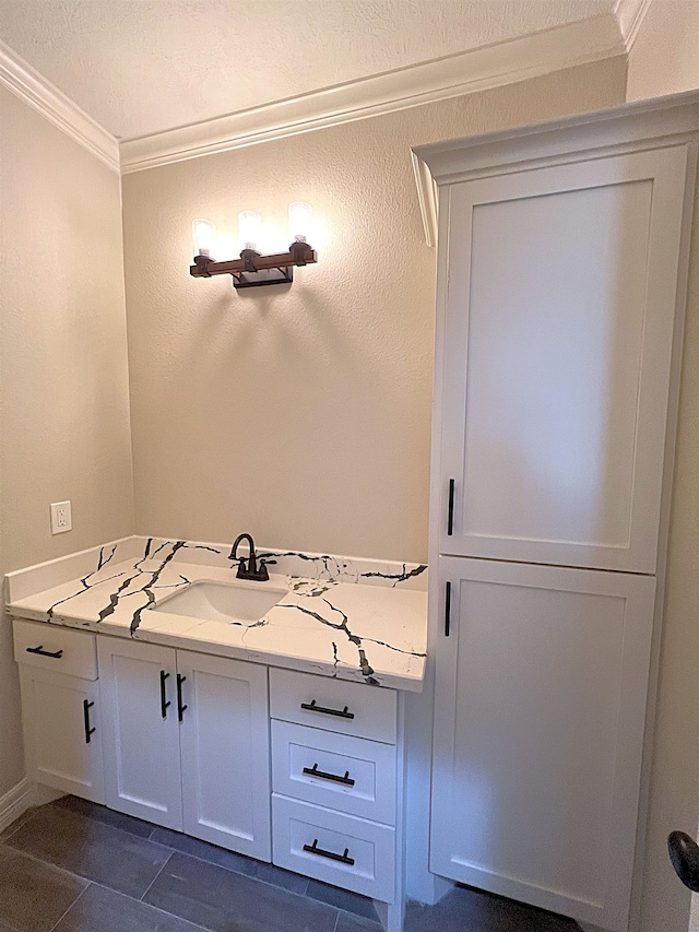 bathroom featuring a textured wall, tile patterned flooring, crown molding, and vanity