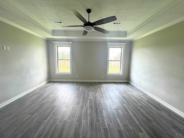 empty room with dark wood-style flooring, a raised ceiling, and visible vents