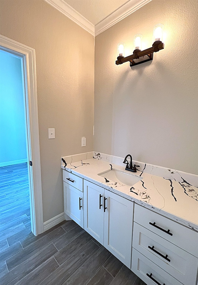 bathroom with ornamental molding, wood finish floors, vanity, and baseboards