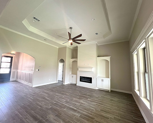 unfurnished living room featuring a tray ceiling, dark wood-style flooring, and a healthy amount of sunlight