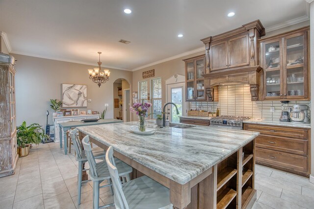 232 Spring Brook Ct, Lumberton, TX 77657 - kitchen with a sink, tasteful backsplash, an island with sink, light stone countertops, and brown cabinets