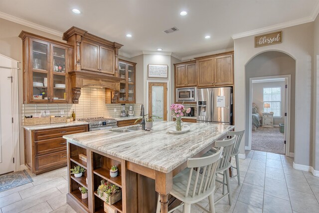232 Spring Brook Ct, Lumberton, TX 77657 - kitchen with appliances with stainless steel finishes, a sink, brown cabinets, light stone counters, and tasteful backsplash