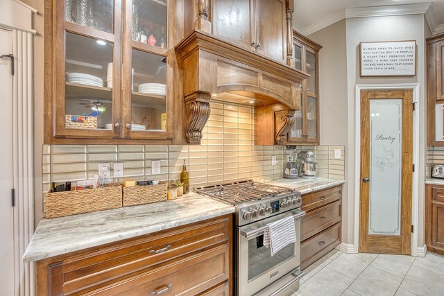 232 Spring Brook Ct, Lumberton, TX 77657 - kitchen featuring high end range, ornamental molding, backsplash, brown cabinetry, and light tile patterned floors
