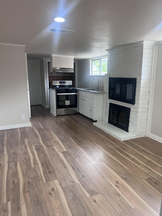 kitchen with white cabinetry, sink, a textured ceiling, electric stove, and light wood-type flooring