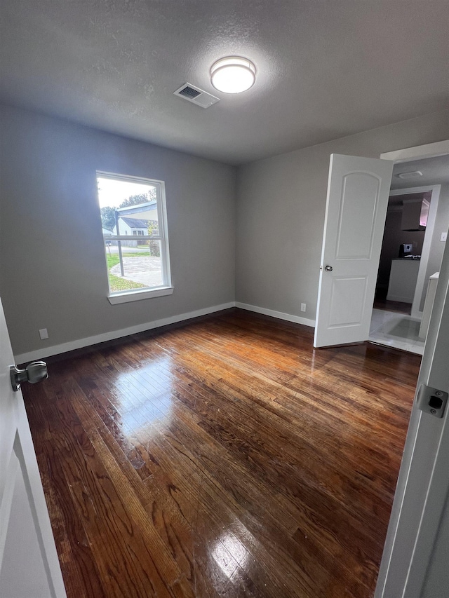 spare room with dark hardwood / wood-style flooring and a textured ceiling