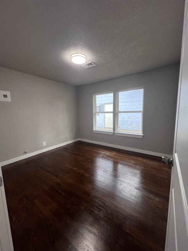 spare room with dark wood-type flooring and a textured ceiling