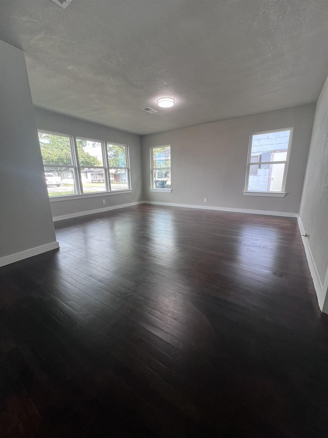 empty room with a textured ceiling and dark wood-type flooring