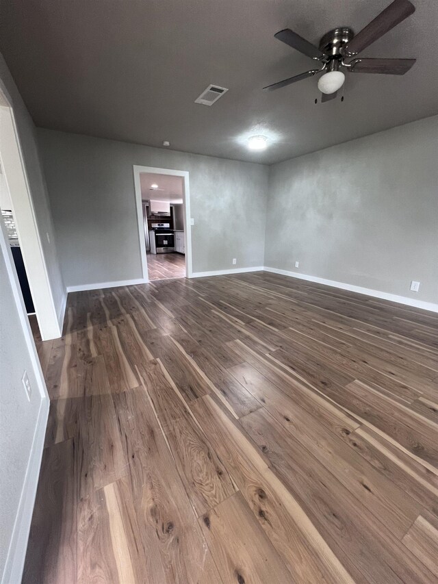 unfurnished living room featuring ceiling fan and dark hardwood / wood-style flooring