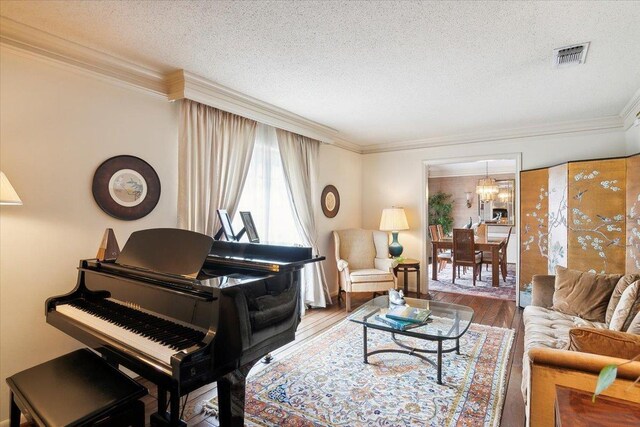 interior space featuring a chandelier, a textured ceiling, hardwood / wood-style flooring, and crown molding