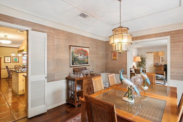 dining space with a textured ceiling, an inviting chandelier, and crown molding