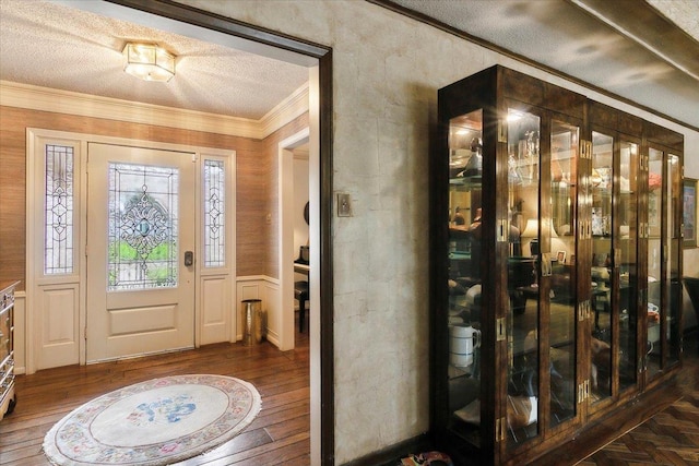 foyer featuring hardwood / wood-style flooring, ornamental molding, and a textured ceiling