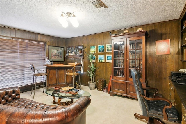 home office with bar, light carpet, wooden walls, and a textured ceiling